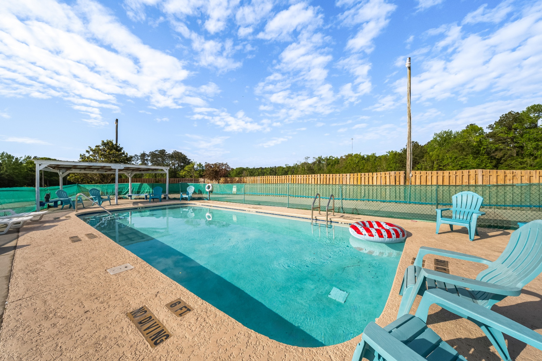 The resort pool with adirondack chairs under a wide Florida sky