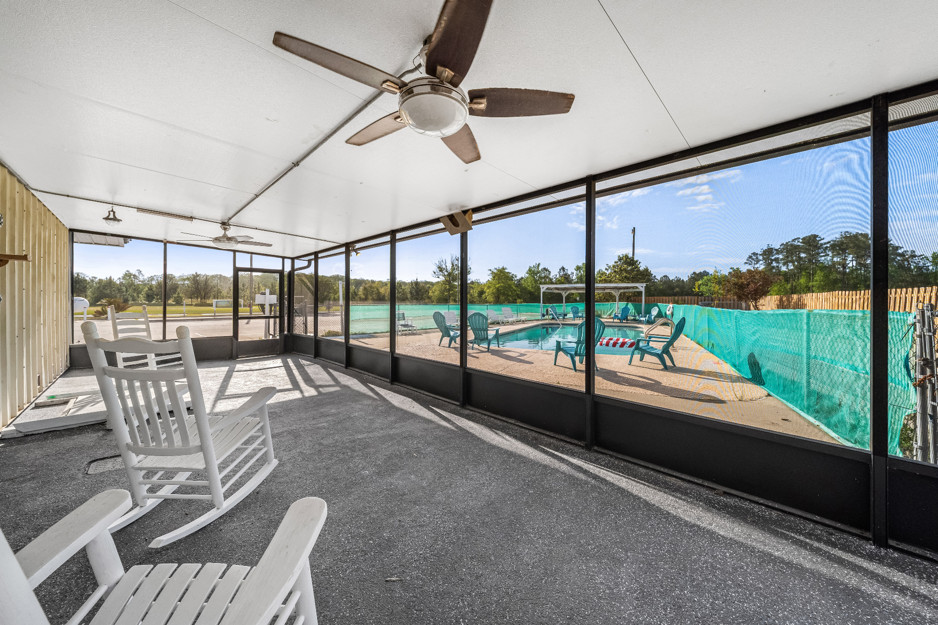 Rocking chairs on the screened porch looking out across the pool deck