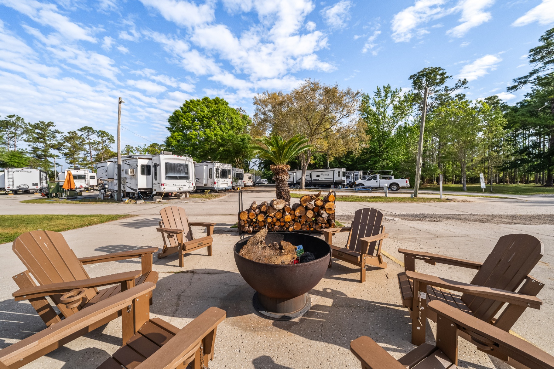 Adirondack chairs gathered around a fire pit between the RV sites