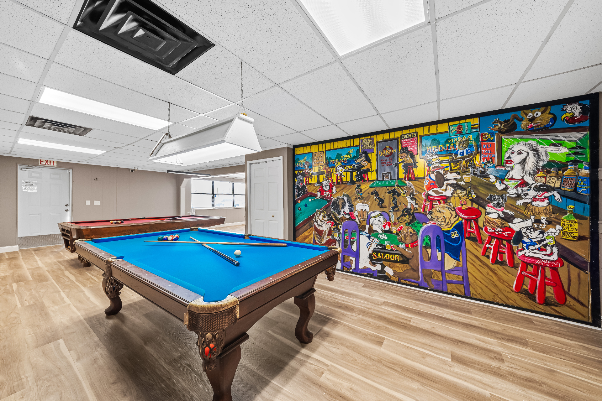 The game room with pool tables and a hand-painted dog saloon mural